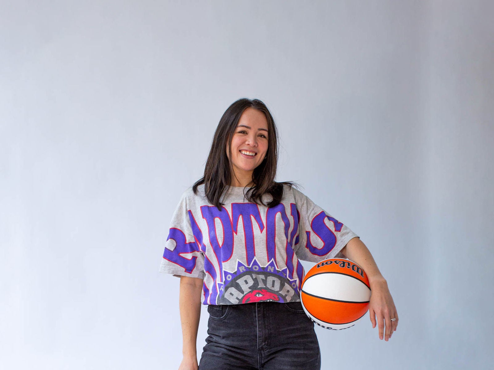 Jacie deHoop, cofounder of The Gist, posing with a Toronto Raptors top and a basketball at her hip.