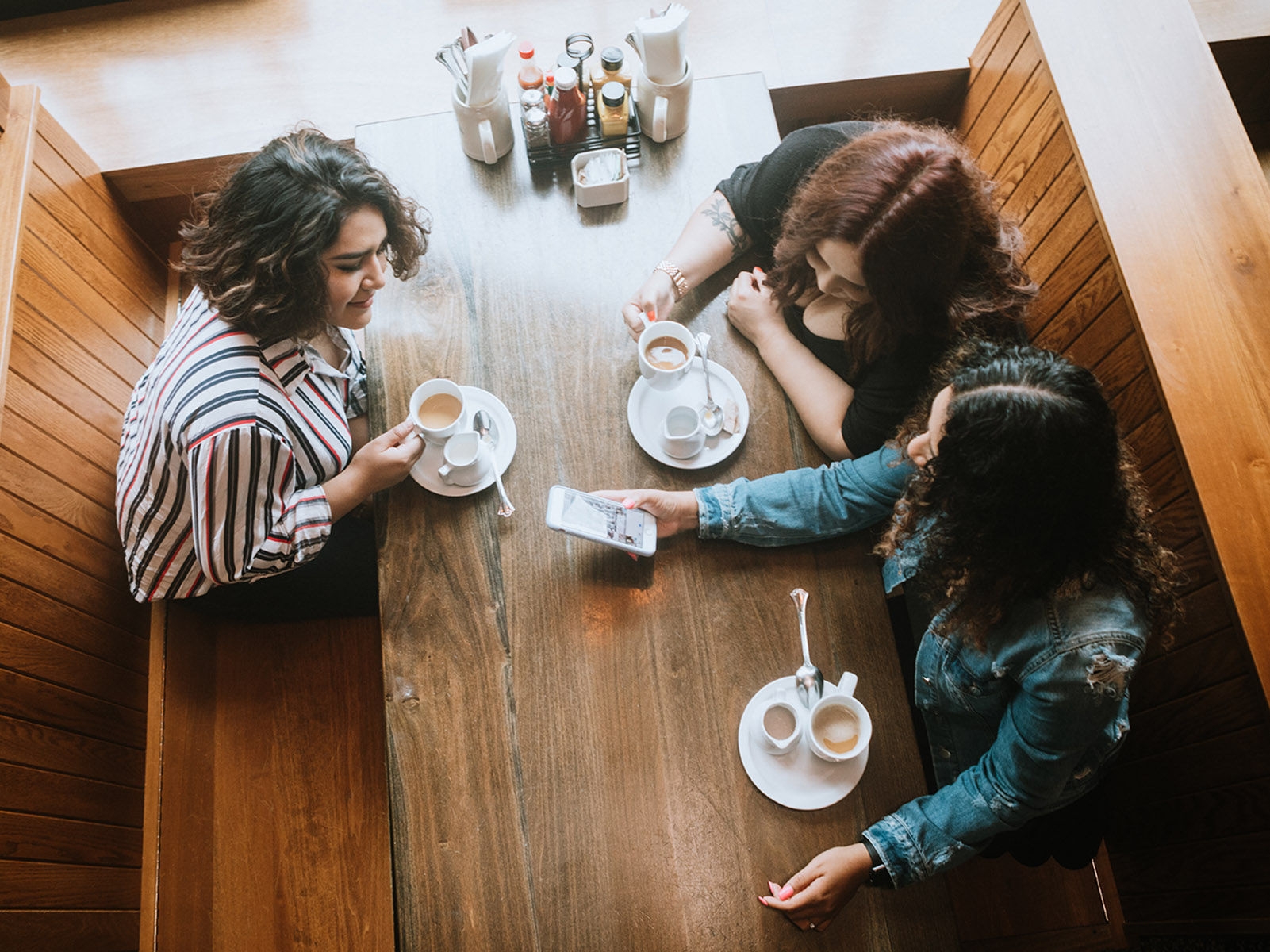 Three women having coffee and chatting at a diner.