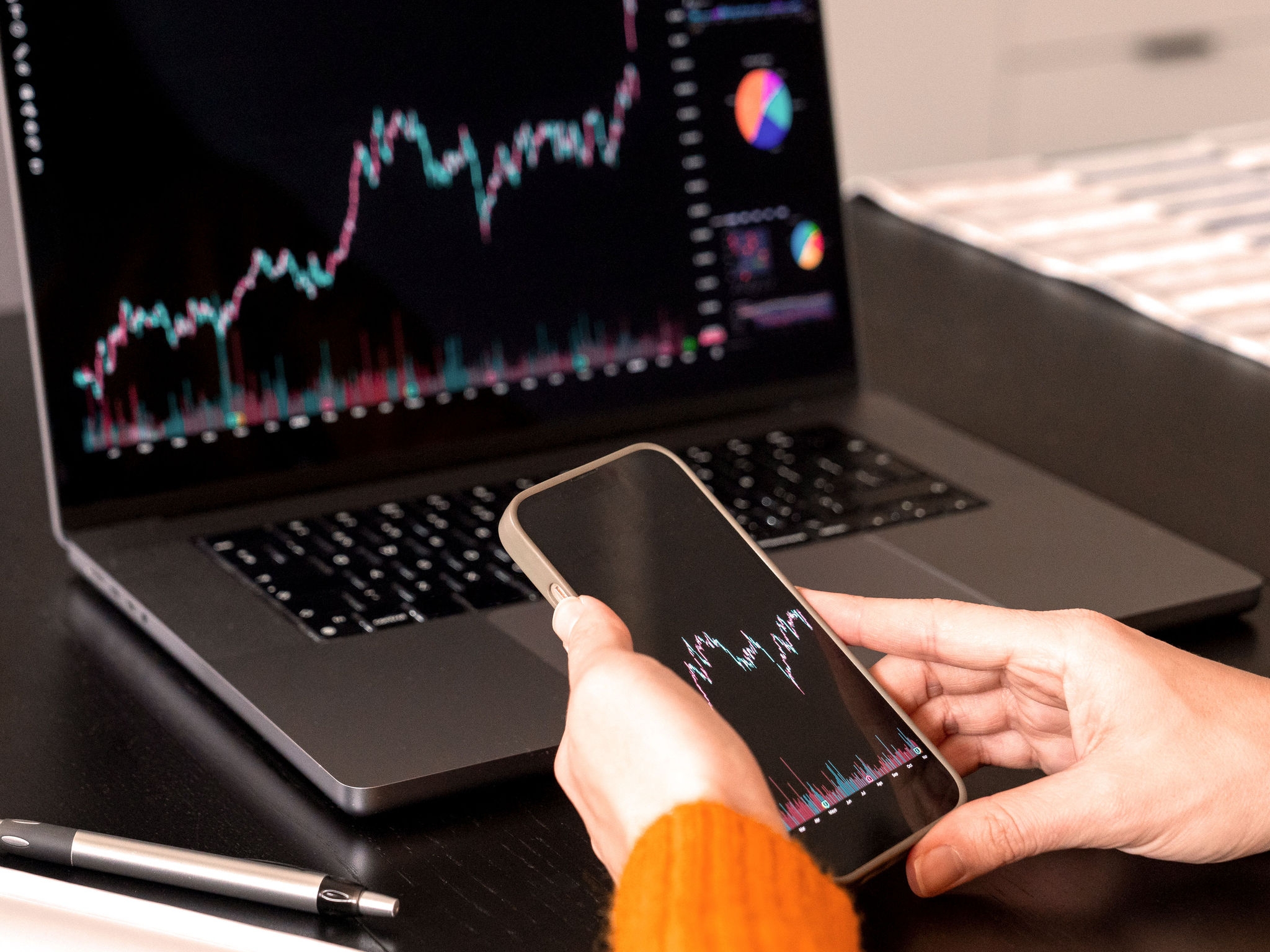 Investor analyzing stock chart using laptop and phone