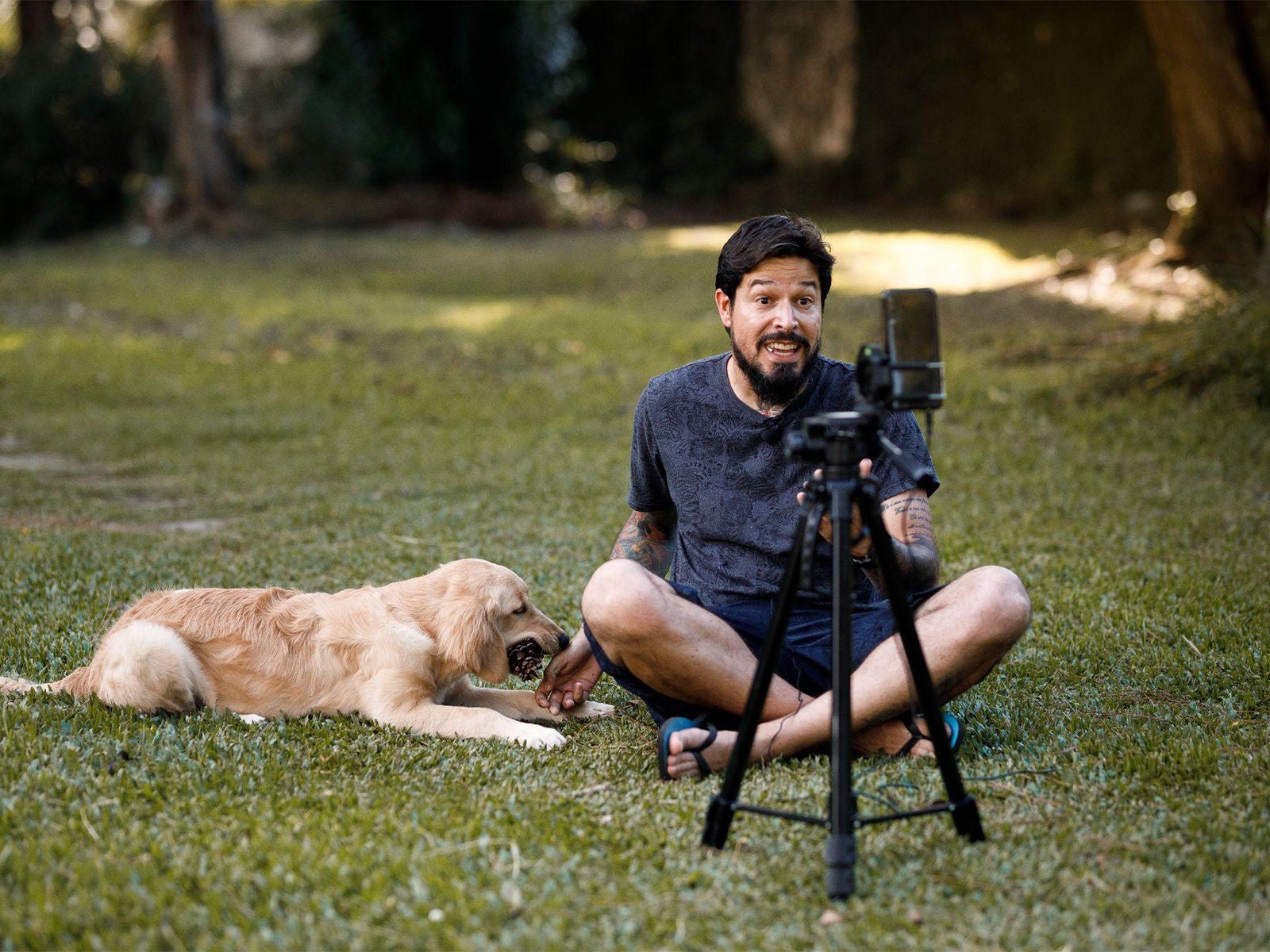 In a park, a man and his dog record content, with his smart phone, for social media.