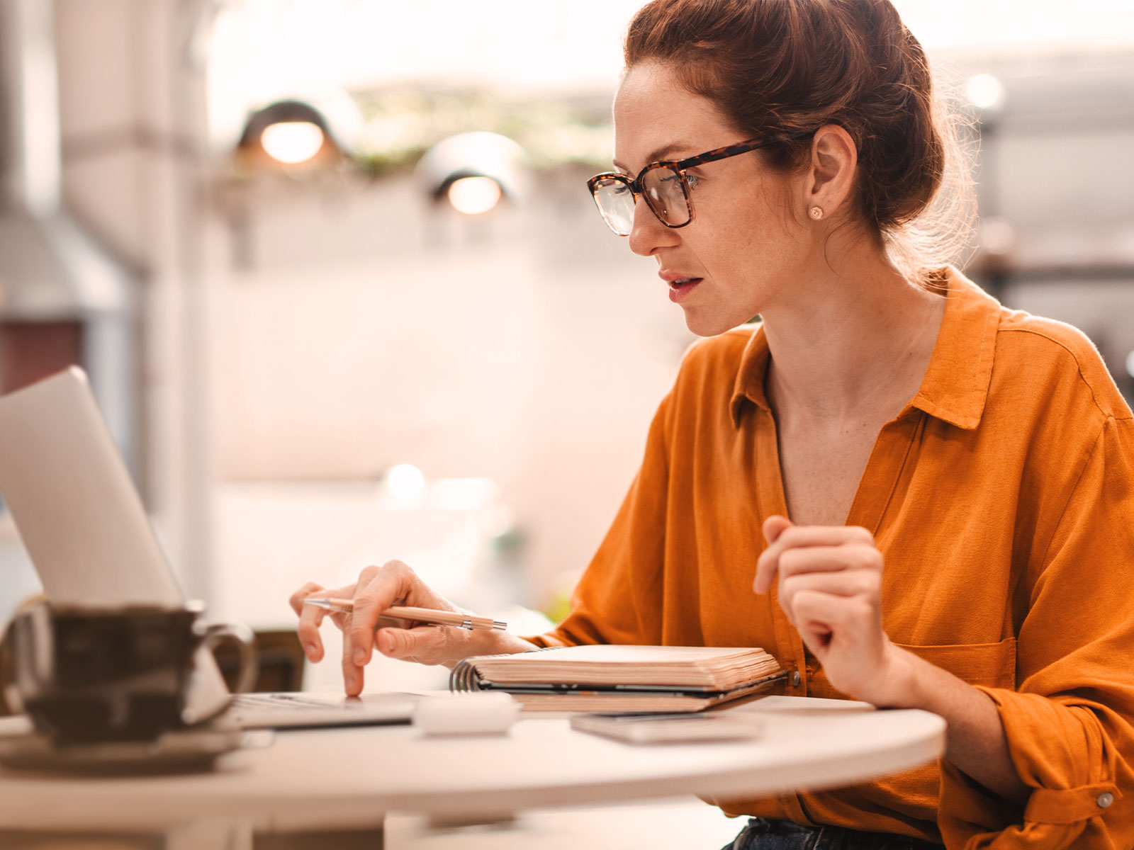 Photo of woman at a table working on her laptop.