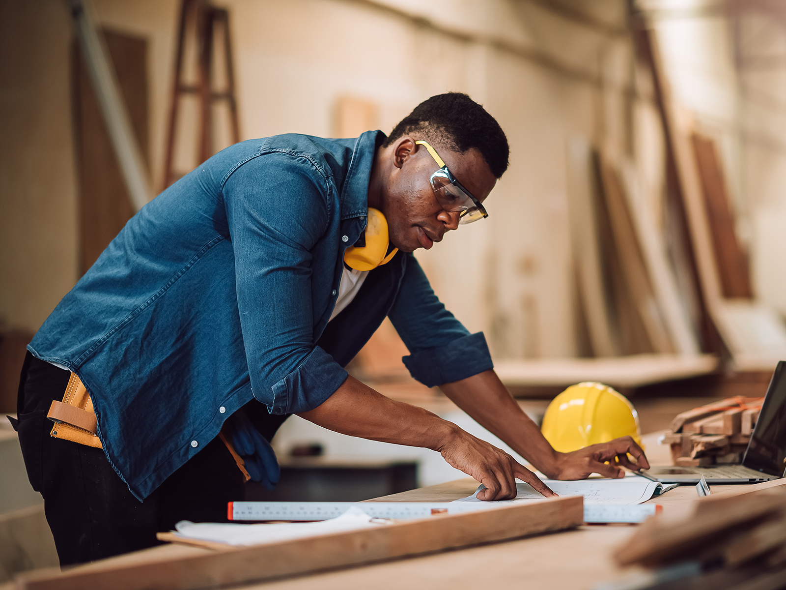 Photo of a carpenter in his workshop reviewing plans on paper.