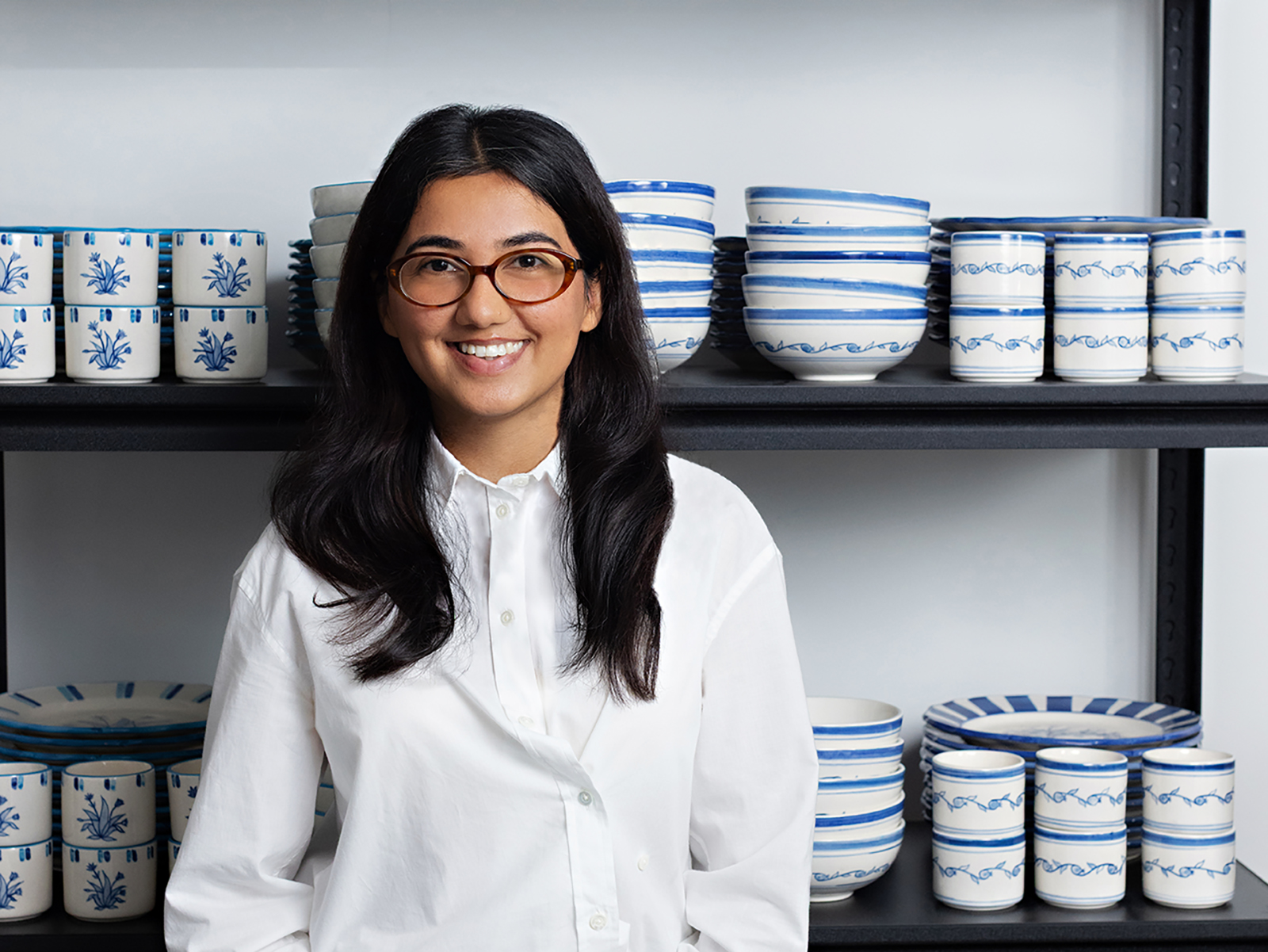 Nairah Awan photographiée devant des étagères présentant la vaisselle artisanale de Studio Purani. Photo de Jessica Blaine Smith.
