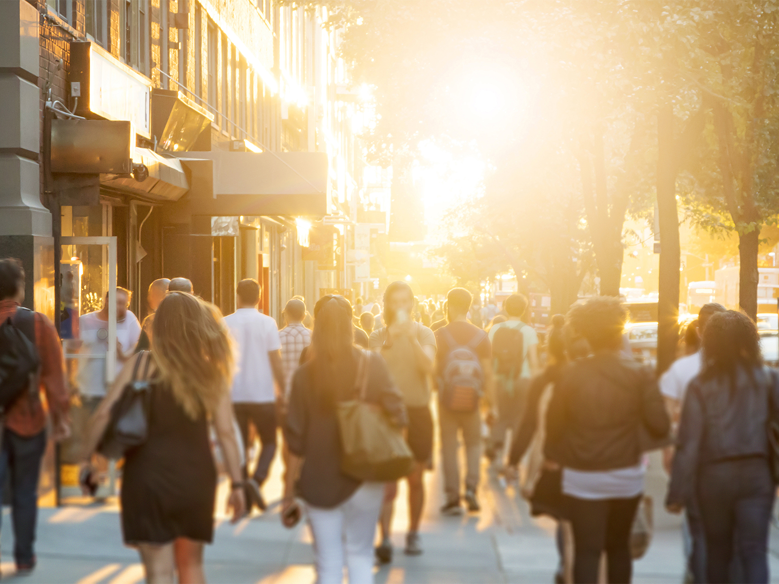 De nombreuses personnes marchent sur un large trottoir d'une ville animée.